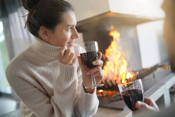  Couple relaxing by the fire enjoying glasses of red wine                              