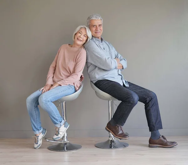 Glückliches Seniorenpaar Sitzt Auf Barhockern Auf Grauem Grund — Stockfoto