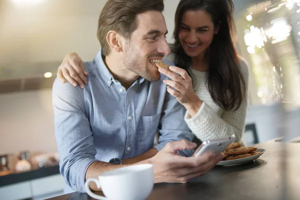 Gorgeous fun couple feeding eachother cookies in modern kitchen