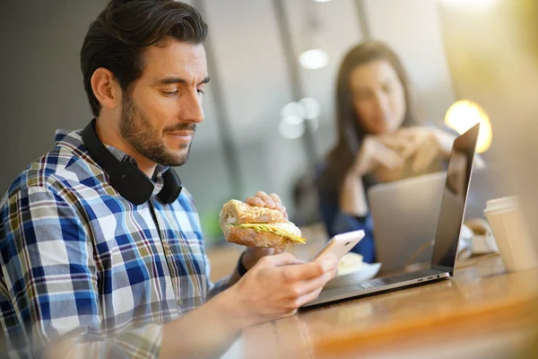 Aantrekkelijke Man Eten Sandwich Tegelijkertijd Moeten Werken Werkplaats Van — Stockfoto