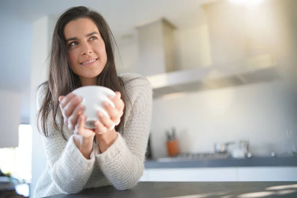 Stunning brunette woman with cup of coffee in modern kitchen