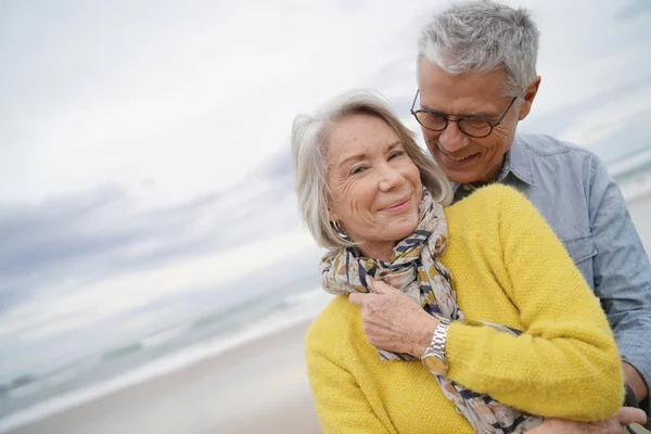 秋天在海滩上拥抱的有吸引力的充满活力的高级夫妇的肖像 — 图库照片