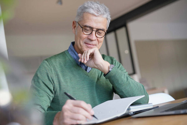  Modern senior man working on laptop at home                              