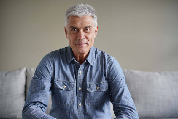  Portrait of casual modern senior man in denim on couch                              