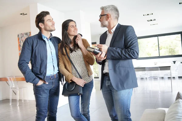 Pareja Con Agente Inmobiliario Visitando Casa Moderna —  Fotos de Stock