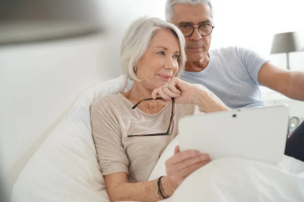 Casal Sénior Relaxante Cama Olhando Para Tablet — Fotografia de Stock