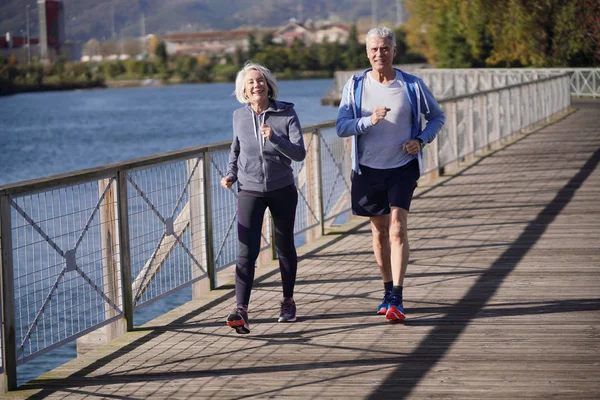Active senior couple speed walking together on bridge