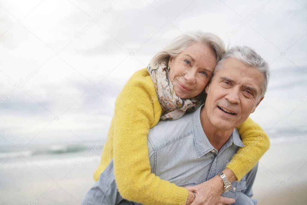 Loving portrait of attractive senior couple on beach in fall                               