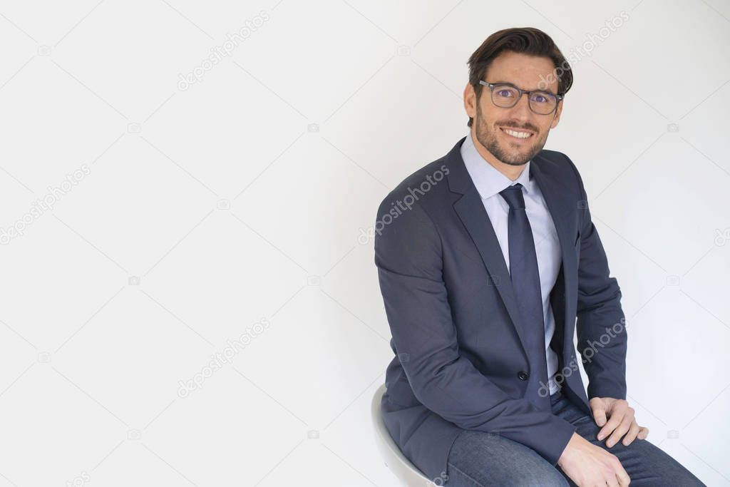 Isolated attractive businessman sitting in suit wearing glasses
