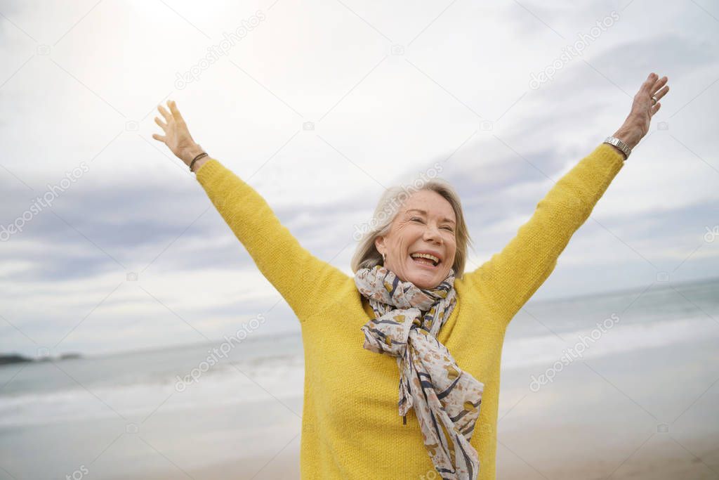  Carefree energetic senior woman playing around on beach in fall                             