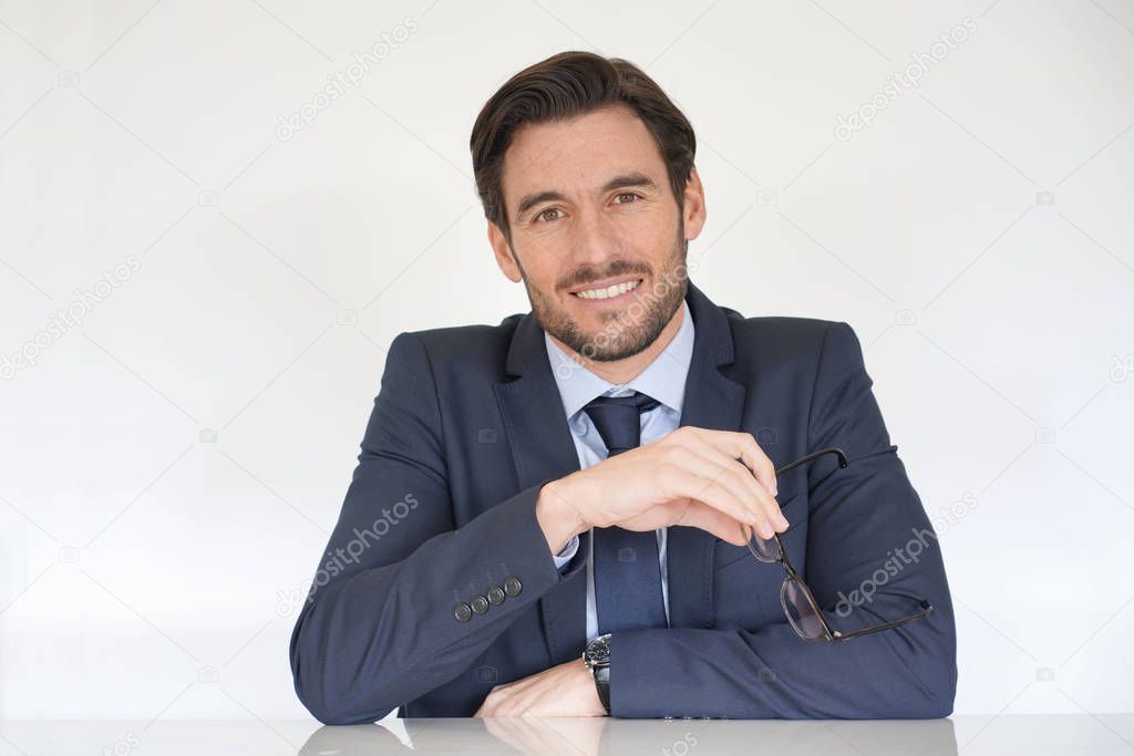 Isolated attractive businessman siting at desk in suit