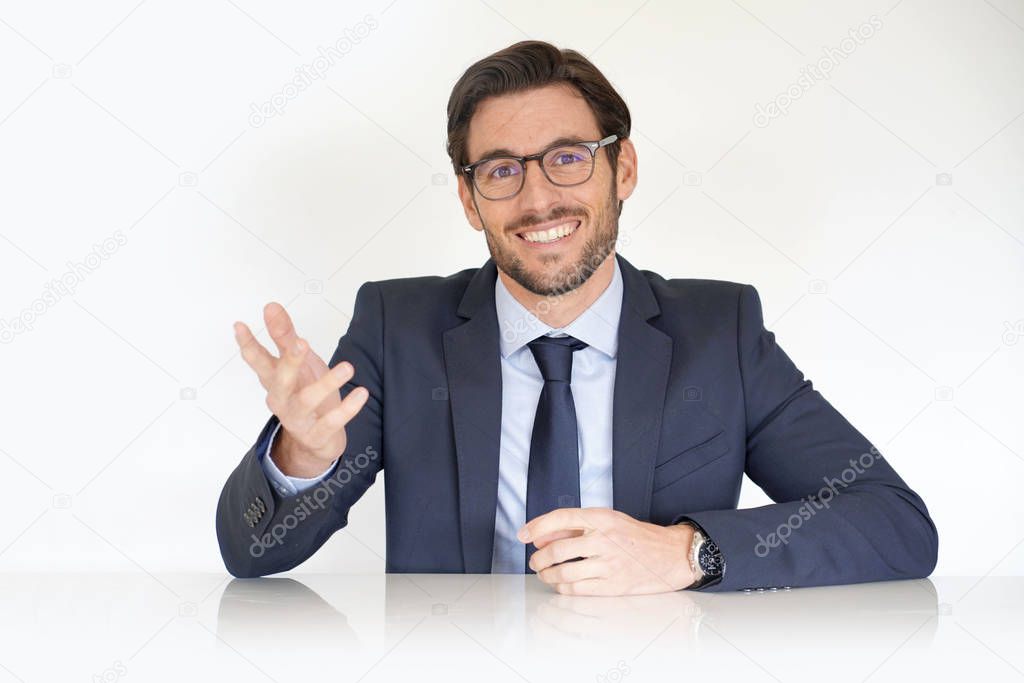 Isolated attractive businessman sitting at desk in suit