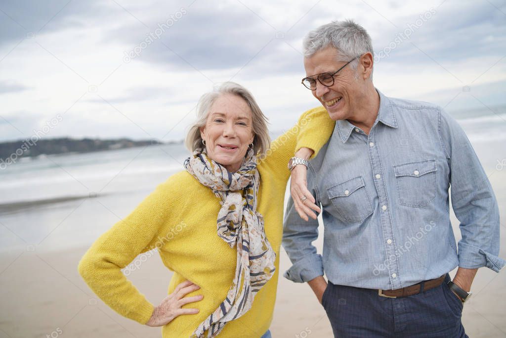 Portrait of happy modern senior couple on beach in fall                              