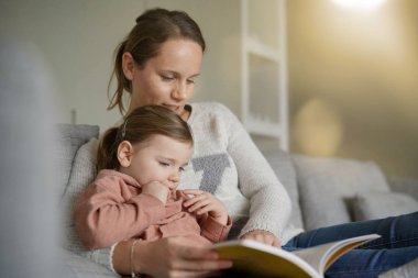 Anne ve genç kızı evde birlikte bir hikaye okuma