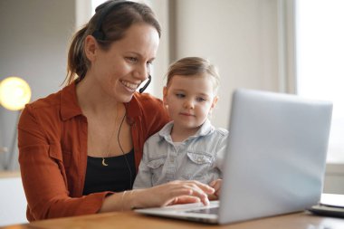 Mother working from home on computer with her young daughter