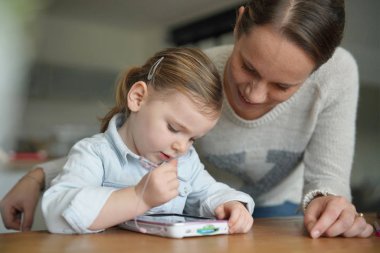 Anne ve kızı eğleniyor evde çocuğun tablet ile oynamak