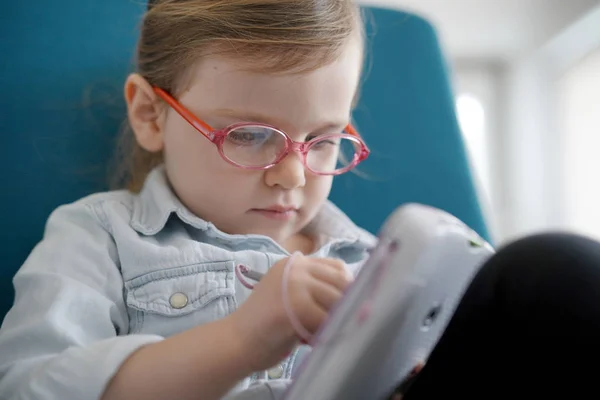 自宅でタブレットで遊んでメガネを身に着けているかわいい若い女の子 — ストック写真