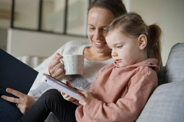 Mamma Och Unga Dotter Läser Och Spelar Tablett Hemma — Stockfoto