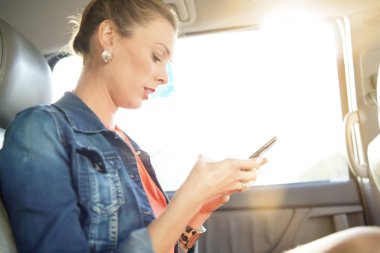 Taksi arkasında oturan cep telefonu bakarak çekici genç kadın 