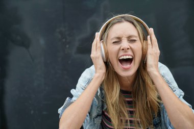 Siyah arka plan üzerinde kulaklık ile müzik dinlemek dinamik genç öğrenci