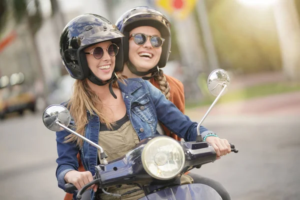 街で一緒にスクーターに乗って幸せな若い女性 — ストック写真