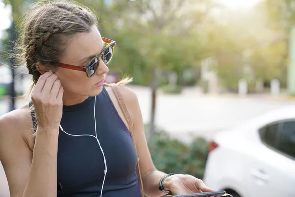 Attractive young woman in sportswear adjusting headphones