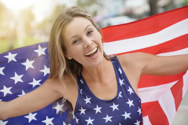 Proud attractive woman flying American flag outdoors