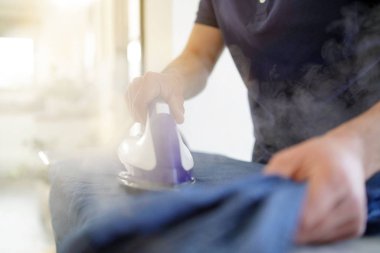 Evde gömlek ütüleme adamın ellerini yakın