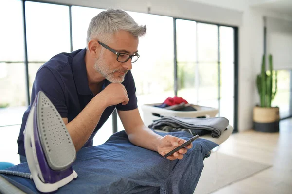 Mannen Mobiltelefon Medan Strykningsservice Hemma — Stockfoto