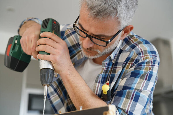 Зрелый человек, использующий силовые упражнения дома
