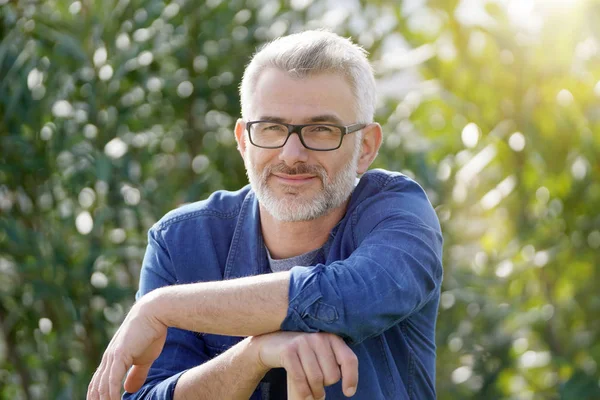 Mann Stützt Sich Auf Harke Sonnigen Garten — Stockfoto