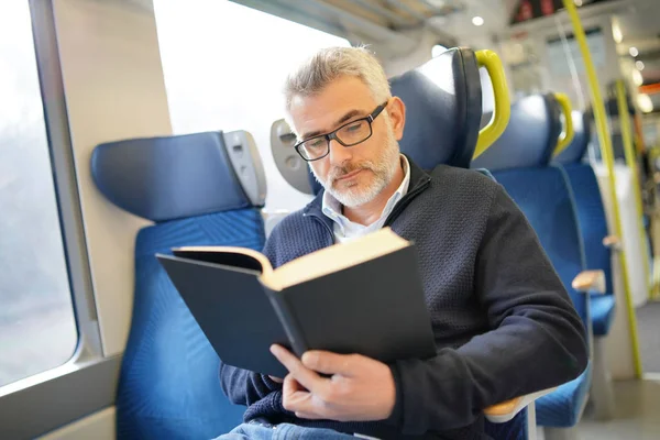 在火车上旅行时 成熟的人看书 — 图库照片
