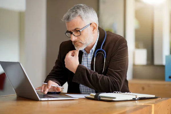 General Practitioner Siedząc Przy Biurku Gabinecie Lekarskim — Zdjęcie stockowe