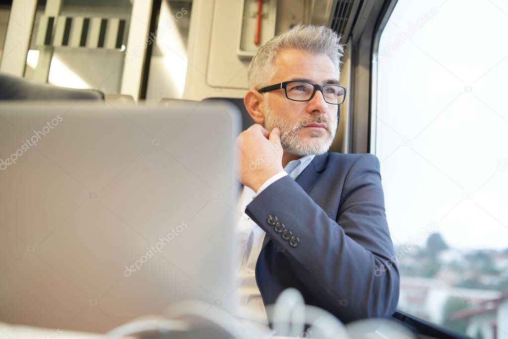 Businessman sitting in train, looking by window