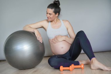 Spor salonunda hamile kadın fitness topu ile oturan, izole