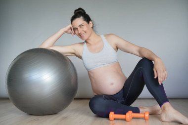 Spor salonunda hamile kadın fitness topu ile oturan, izole
