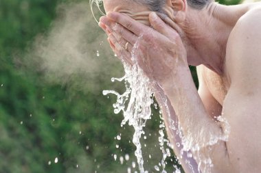 Portrait of topless man splashing face with water clipart