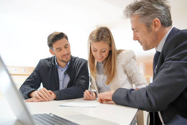 Couple signing contract with real estate agent