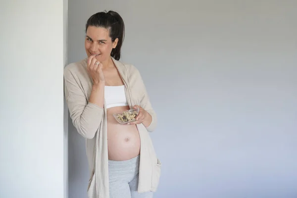 Pregnant woman eating cereals, isolated