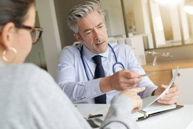 Doktor klinik ofisinde hasta ile sonuçları geçiyor