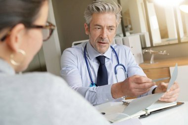 Doktor klinik ofisinde hasta ile sonuçları geçiyor