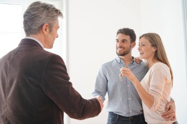 Emlakçı mutlu yeni ev sahiplerine anahtarları teslim