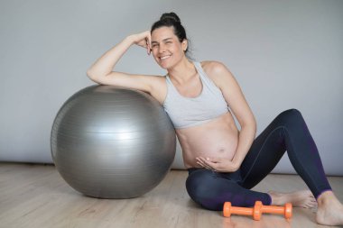 Spor salonunda hamile kadın fitness topu ile oturan, izole