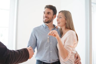 Emlakçı mutlu yeni ev sahipleri ile el sıkışma