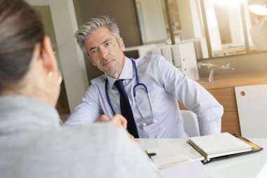 Doktor klinik ofisinde hasta ile sonuçları geçiyor