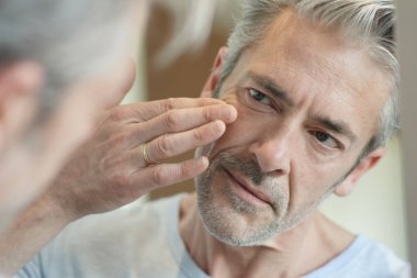 Evde aynaya bakan olgun yakışıklı adam Portresi