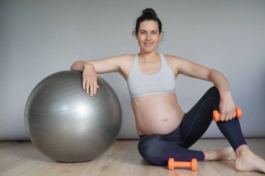 Spor salonunda hamile kadın fitness topu ile oturan, izole