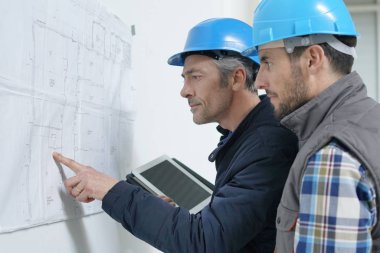 Mimar ve inşaat işçisi proje planı üzerinden gidiyor