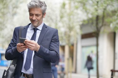 İşadamı cep telefonu ile yürüyerek gidip