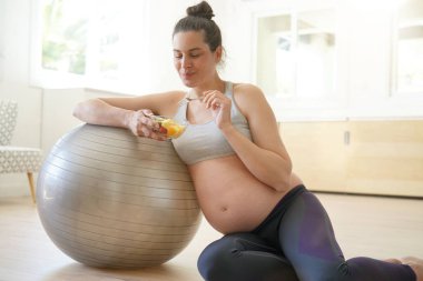 Fitness hamile kadın fitness topu ile meyve salatası yeme